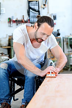 Worker in wheelchairworkong in a carpenter`s workshop