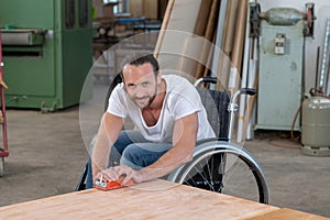 Worker in wheelchairworkong in a carpenter`s workshop