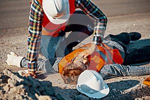 Worker in white helmet checking life functions of an injured man