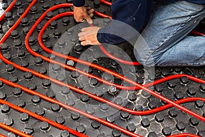 Worker who instal tubes of radiant underfloor heating installation