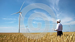 Worker of a wind power plant in a yellow wheat field