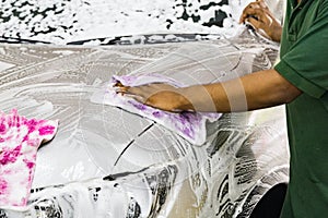 Worker wipe clean car using detergent soap foam with cloth