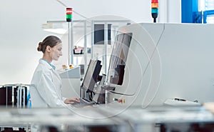 Worker woman in factory operating a soldering machine for electronics production