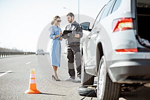 Worker with woman near the broken car on the highway