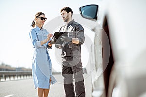 Worker with woman near the broken car on the highway