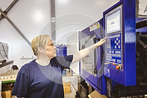 A worker woman presses a button and starts an automatic manufacturing process in a factory