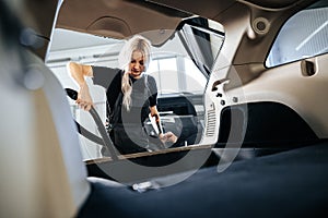 Worker woman vacuum cleaning dust interior inside car in car wash.