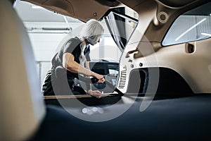 Worker woman vacuum cleaning dust interior inside car in car wash.