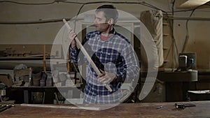 Worker in work shirt measures wooden board with long yellow ruler on a workbench