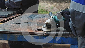 Worker on workbench processes iron sheets with grinding tool and sparks fly. Close-up video. Authentic workflow.