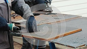 Worker on workbench processes iron sheets with grinding tool and sparks fly. Close-up video. Authentic workflow.