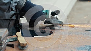 Worker on workbench processes iron sheets with grinding tool and sparks fly. Close-up video. Authentic workflow.