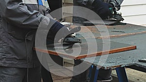 Worker on workbench processes iron sheets with grinding tool and sparks fly. Close-up video. Authentic workflow.