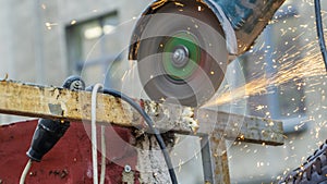 Worker working with angle grinder. Electric wheel grinding on steel structure. Sparks. Defocused background.