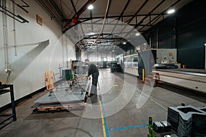 a worker working in a modern industry prepares material for processing on a cnc machine, wears a protective mask on his