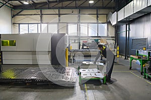 a worker working in a modern industry prepares material for processing on a cnc machine, wears a protective mask on his