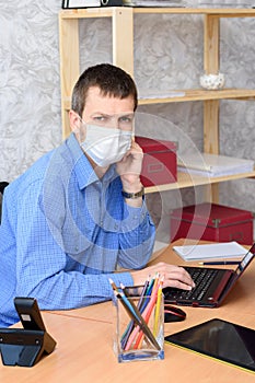 Worker working remotely in a computer in a medical mask looked into the frame