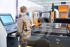 Worker on workplace of laser cutting complex for metal