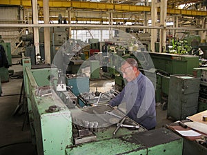 a worker works on a lathe in a Soviet era machine shop