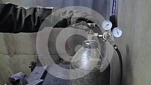 A worker in the workshop opens the valve of the oxygen or gas tank.