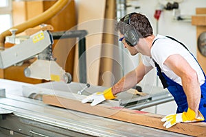 worker in workshop using saw machine