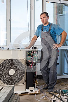 A worker in workwear sets air conditioner in new