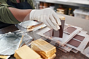 Worker wrapping chocolate bars from molds in gold foil