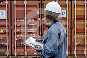 Worker writing on clipboard in shipping docks
