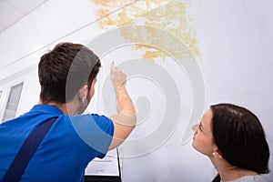 Worker Writing On Clipboard With Woman Standing