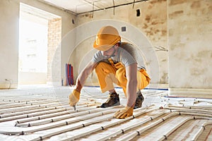 Worker in yellow colored uniform installing underfloor heating system