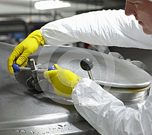 Worker in yellow gloves closing industrial process tank