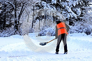 A worker in a yellow vest cleans the city street, park from fresh snow in winter. Dnipro, Dnipropetrovsk, Ukraine