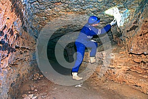 Workerman with helmet and protective suit using glowes and strong head lamp.