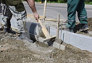 Workers align the cement near the installed curbs.
