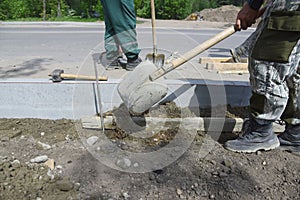 Workers align the cement near the installed curbs.