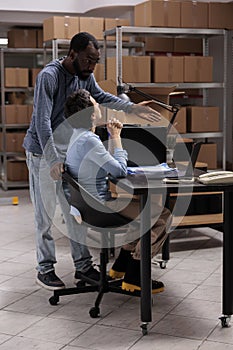 Workers analyzing transportation logistics while checking metallic box delivery order on laptop