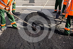 Workers on Asphalting paver machine during Road street repairing works. Street resurfacing. Fresh asphalt construction