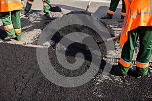 Workers on Asphalting paver machine during Road street repairing works. Street resurfacing. Fresh asphalt construction