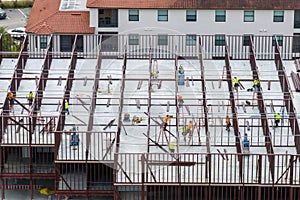 Workers assembling metal frame building at industrial construction site. Housing development in America. Real estate