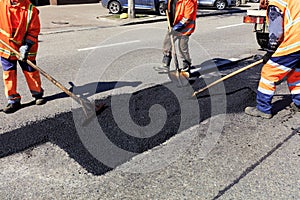 The workers` brigade clears a part of the asphalt with shovels in road construction