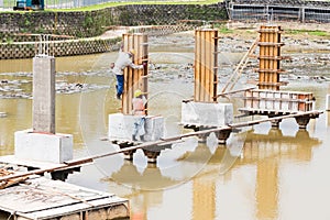 Workers building bridge foundation across lake