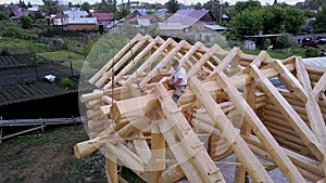 Workers are building on frame roof of wooden house. Clip. Top view of workers building roof frame of wooden country