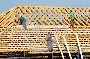 Workers are building the roof of the house from wood