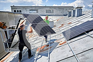 Workers building solar panel system on roof of house. Installers carrying photovoltaic solar module