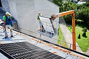 Workers building solar panel system on roof of house. Installers carrying photovoltaic solar module