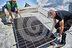 Workers building solar panel system on roof of house. Men installing photovoltaic solar module