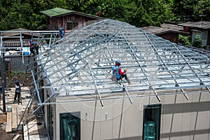 Workers are building a steel roof frame on high.