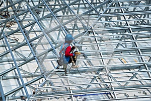 Workers are building a steel roof frame on high.