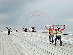 Workers Carry Solar PV Panel on Roof Installation