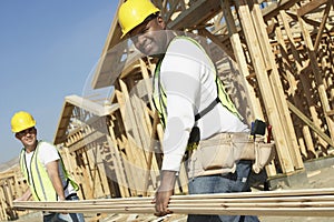 Workers Carrying Boards At Construction Site